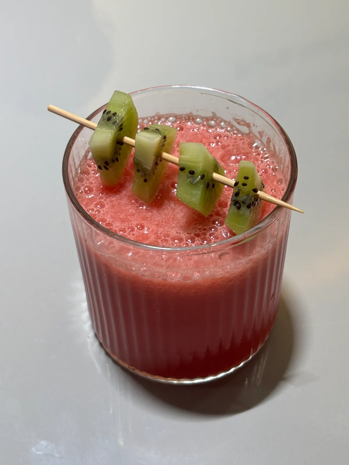 Kiwi melon crush garnished with a skewer of kiwi
