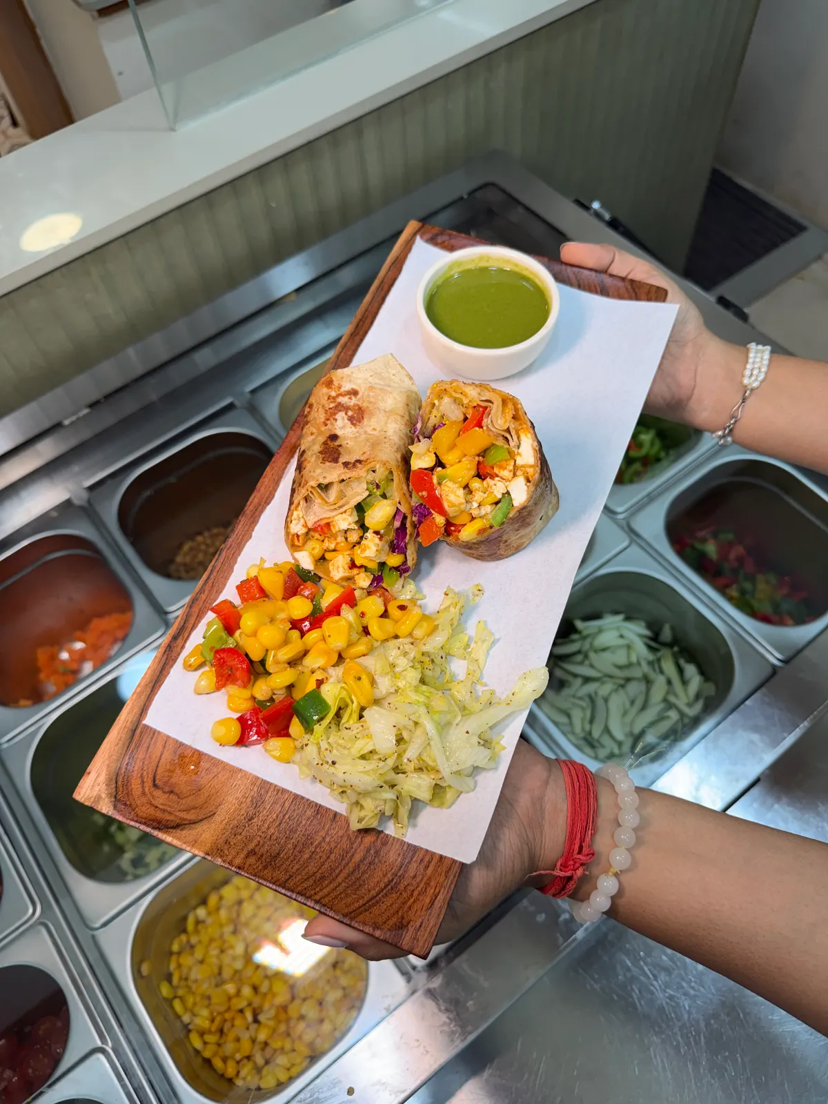 Wrap platter with green chutney and corn, held over the café's salad counter